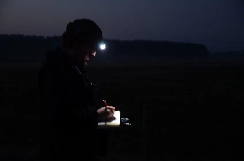 En person med pannlampa står i mörker. Foto.